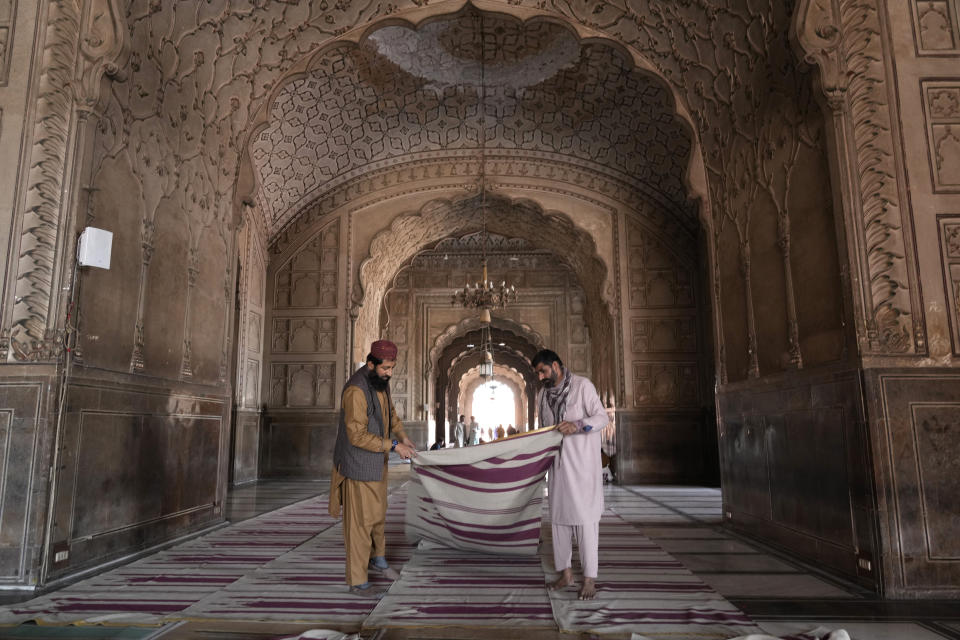 Workers clean the carpet in the historical 'Badshahi' mosque in preparation for the upcoming Lahore, Pakistan, Saturday, March 9, 2024. (AP Photo/K.M. Chaudary)