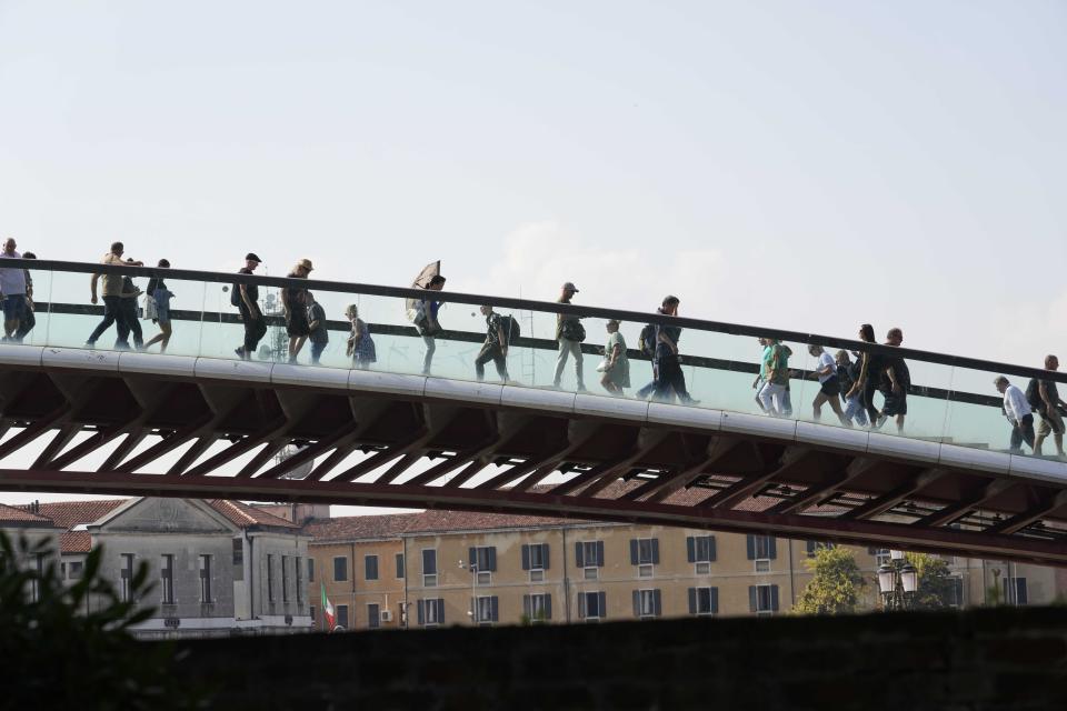 Tourists walk across a bridge, in Venice, Italy, Wednesday, Sept. 13, 2023. The Italian city of Venice has been struggling to manage an onslaught of tourists in the budget travel era. The stakes for the fragile lagoon city are high this week as a UNESCO committee decides whether to insert Venice on its list of endangered sites. (AP Photo/Luca Bruno)