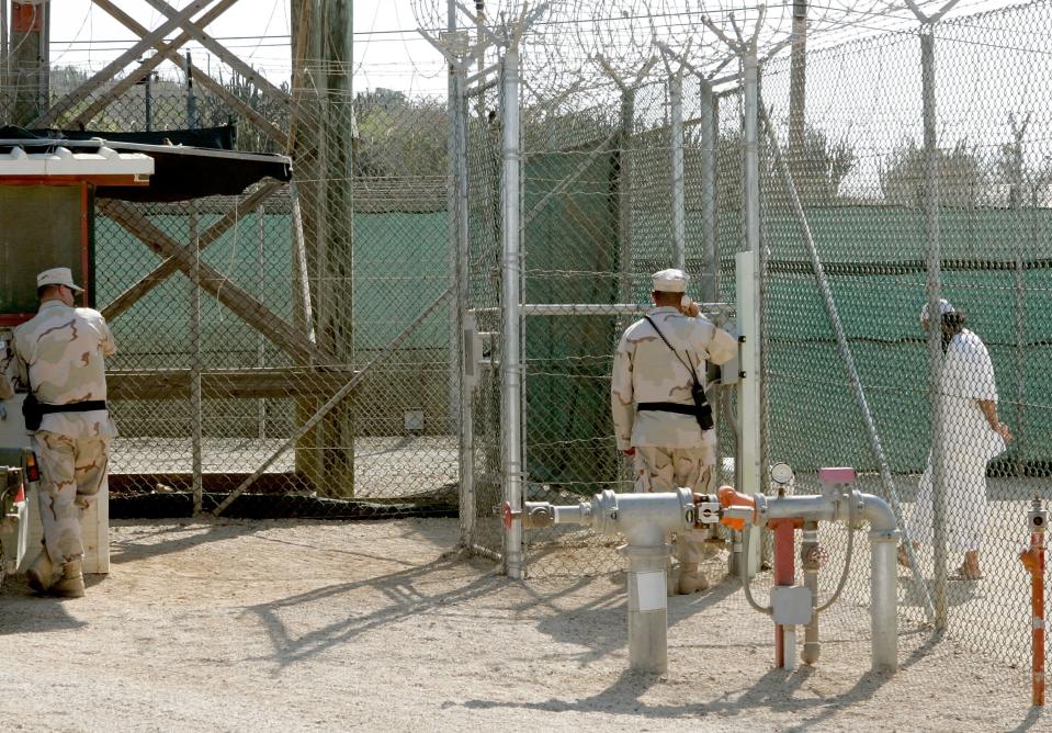 GUANTANAMO BAY, CUBA - MAY 09: (IMAGE REVIEWED BY U.S. MILITARY PRIOR TO TRANSMISSION) Two members of the U.S. Military stand near a detainee at Camp 4 inside of Camp Delta May 9, 2006 in Guantanamo Bay, Cuba. Camp Delta was first occupied on April 28, 2002, when 300 detainees previously held at Camp X-Ray were transferred to Camp Delta. The rest of the detainees were moved on April 29. Camp X-Ray closed down on that same day. (Photo by Mark Wilson/Getty Images)