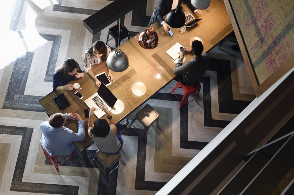 Young Chinese colleagues working together in a busy co-working space from above