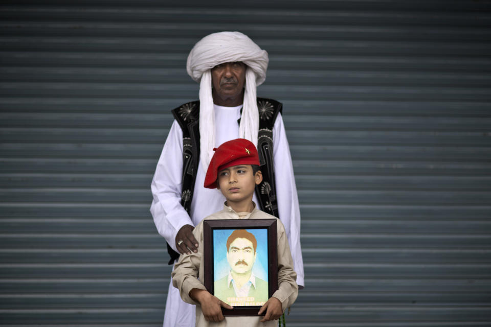 Mohammed Qadir, 62, and his grandson Meer, 7, pose for a portrait holding a photograph of his dead father Jaleel, who went missing in 2010 and reported dead in 2013, while he and other relatives take a break from a long march protest, in Rawalpindi, Pakistan, Friday, Feb. 28, 2014. They are part of two dozen activists from the impoverished southwestern province of Baluchistan who walked roughly 3,000 kilometers (1,860 miles) to the capital of Islamabad to draw attention to alleged abductions of their loved ones by the Pakistani government. (AP Photo/Muhammed Muheisen)