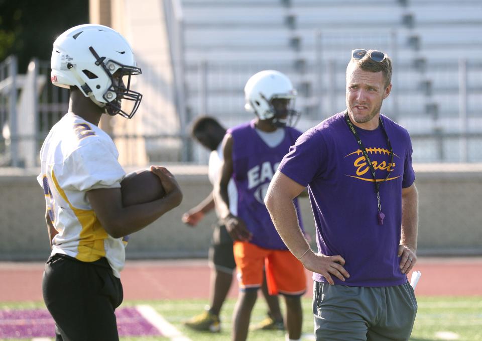 East co-coach Steve Flagler works with quarterback Levi Wallace during practice.