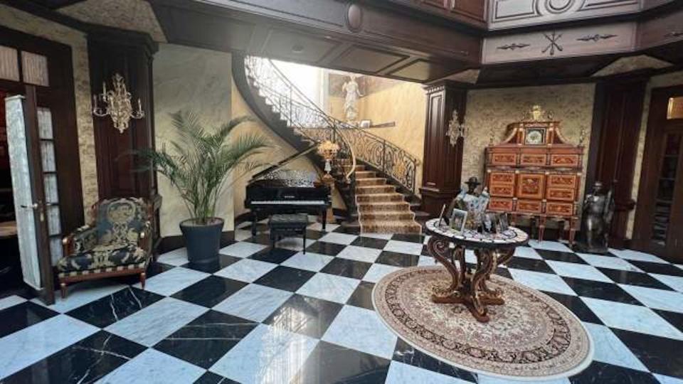 A grand staircase leads down to an apparent hallway with black and white tiles