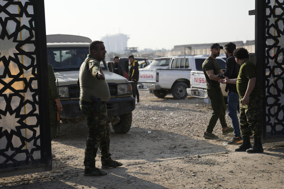 Members of an Iraqi Shiite militant group stand outside the headquarters of the Popular Mobilization Force after it was hit by an airstrike in Baghdad, Iraq, Thursday, Jan. 4, 2024. The Popular Mobilization Force - a coalition of militias that is nominally under the control of the Iraqi military - announced in a statement that its deputy head of operations in Baghdad, Mushtaq Taleb al-Saidi, or "Abu Taqwa," had been killed in the strike. (AP Photo/Hadi Mizban)