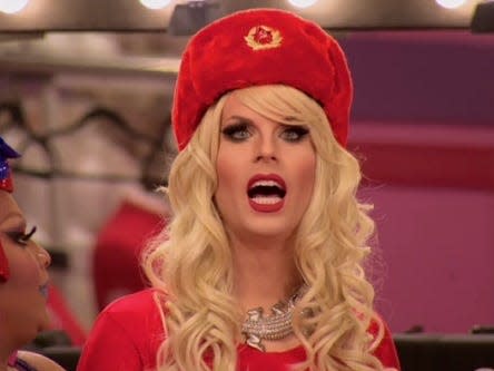 Katya in red hat and red shirt and blonde wig on drag race