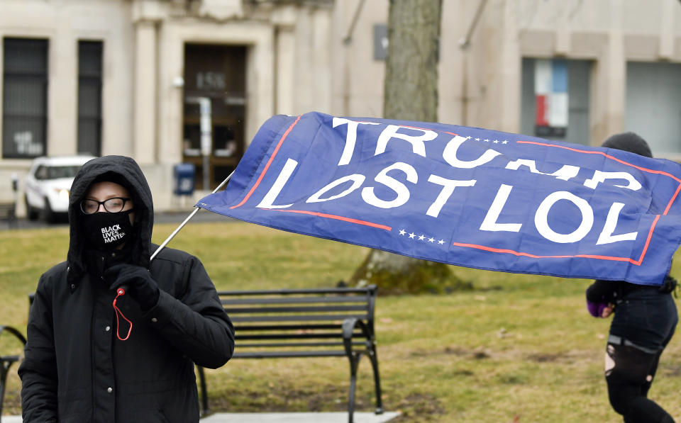 Christina Janowitz, of Guilderland, N.Y., from the group All Of Us holds a flag while counter protesting a Trump rally ahead of the inauguration of President-elect Joe Biden and Vice President-elect Kamala Harris at the New York State Capitol Sunday, Jan. 17, 2021, in Albany, N.Y. (AP Photo/Hans Pennink)