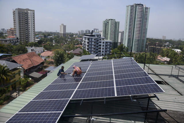 FILE - Workers install solar panels on the roof of a residential apartment in Kochi, southern Kerala state, India, March 22, 2023. India will require $900 billion over the next 30 years to move away from coal mines and thermal plants, a New Delhi based think tank said in a report Thursday, March 23, 2023. Ensuring that everyone can come along in the clean energy shift that's needed to stop the worst harms of climate change and guaranteeing new work opportunities for those in fossil fuel industries has been a major consideration for climate and energy analysts. (AP Photo/R S Iyer, File)