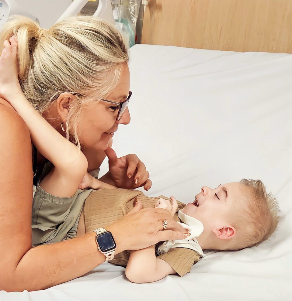 Oskar with his legs on his Nana's shoulders in a hospital bed. 