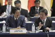 Japan's Prime Minister Shinzo Abe, left, and Minister of Economy, Trade, Industry Toshimitsu Motegi, right, share a light moment during an opening session of the Comprehensive and Progressive Trans-Pacific Partnership (CPTPP) in Tokyo, Saturday, Jan. 19, 2019. Trade ministers of a Pacific Rim trade bloc are meeting in Tokyo, gearing up to roll out and expand the market-opening initiative. (AP Photo/Eugene Hoshiko)