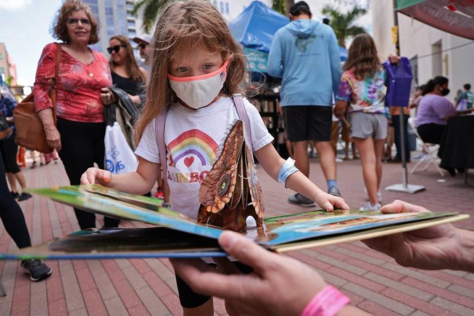 Shay Yuen, de 4 años, mira un libro desplegable mientras su padre, Brendon Yuen, de 35 años, le ayuda a sostenerlo en la Feria del Libro de Miami del año pasado, que fue un evento híbrido, tanto en línea como en persona.