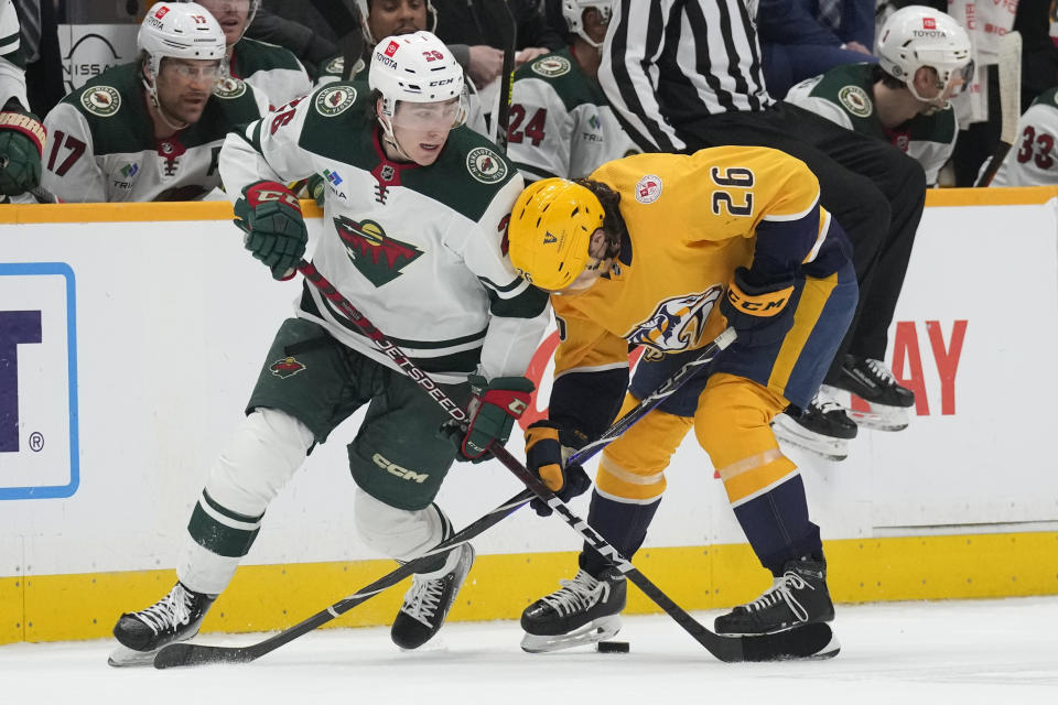 Minnesota Wild center Connor Dewar, left, and Nashville Predators's Philip Tomasino battle for the puck during the first period of an NHL hockey game Thursday, April 13, 2023, in Nashville, Tenn. (AP Photo/Mark Humphrey)