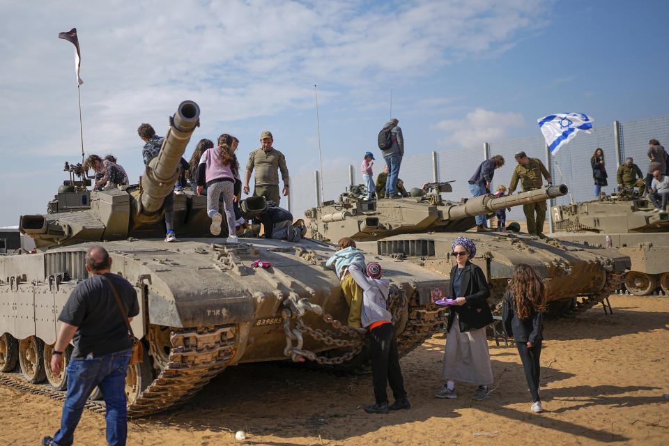 Israelis stand on tanks during an event for families of reservists outside a military base in southern Israel, Tuesday, Feb. 27, 2024. Israel has called up tens of thousands of reservists for its war in Gaza, separating the soldiers from their families for weeks at a time. (AP Photo/Ohad Zwigenberg)