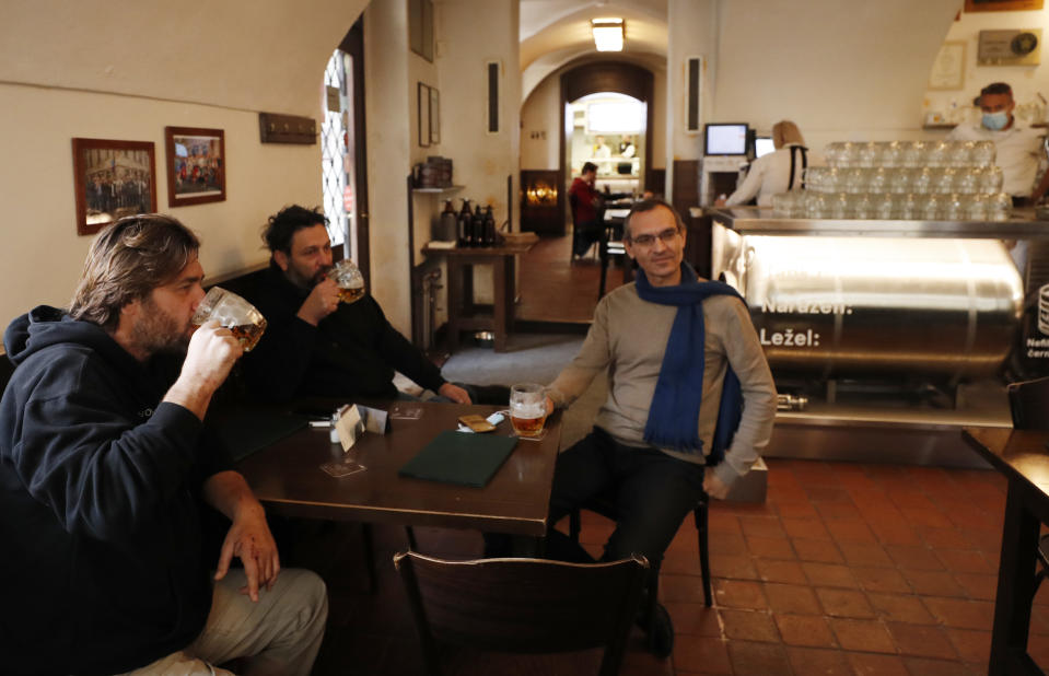 Men enjoy a beer at a pub in Prague, Czech Republic, Thursday, Dec. 3, 2020. A sign of normalcy has returned to the Czech Republic ahead of the Christmas period after the government eased some of its most restrictive measures imposed to contain the recent massive surge of coronavirus infections. On Thursday all stores, shopping malls, restaurants, bars and hotels were allowed to reopen. (AP Photo/Petr David Josek)