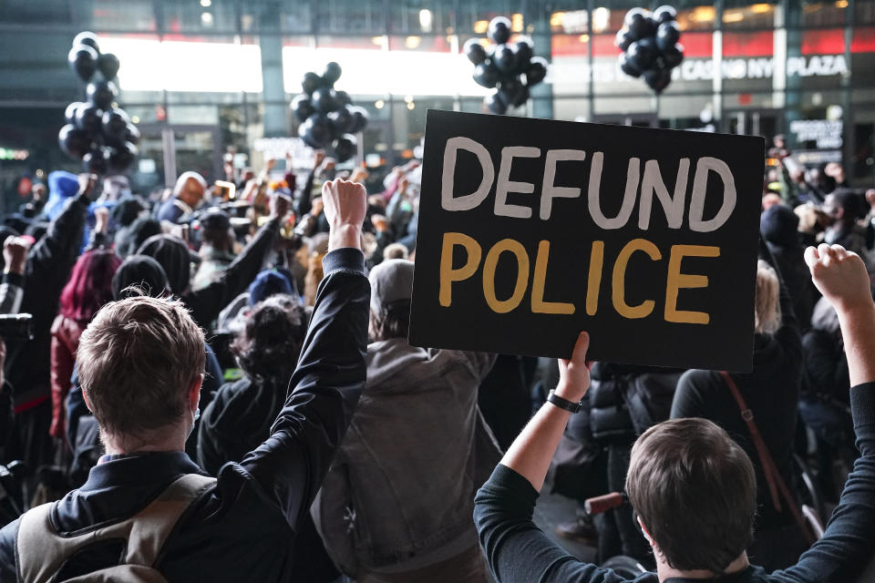 FILE - In this Wednesday, Oct. 14, 2020, file photo, a protester holds a sign that reads "Defund Police" during a rally for the late George Floyd outside Barclays Center, in New York. Demonstrators gathered on what would have been Floyd's 47th birthday to call for action in correcting systemic racism in policing and for criminal justice reform. Responses to the coronavirus pandemic and police brutality dominated legislative sessions in 2020 and led to many new laws that will take effect in the new year. (AP Photo/John Minchillo, File)