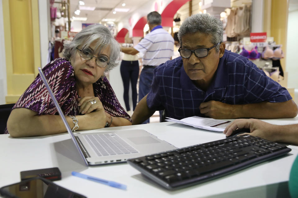 MIAMI, FL - NOVEMBER 01:  Isabel Diaz Tinoco  (L) and Jose Luis Tinoco look at a computer as Otto Hernandez, an insurance agent from Sunshine Life and Health Advisors, shows them the different insurance plans available under the Affordable Care Act at a store setup in the Mall of Americas  on November 1, 2017 in Miami, Florida. The open enrollment period to sign up for a health plan under the Affordable Care Act started today and runs until Dec. 15.  (Photo by Joe Raedle/Getty Images)