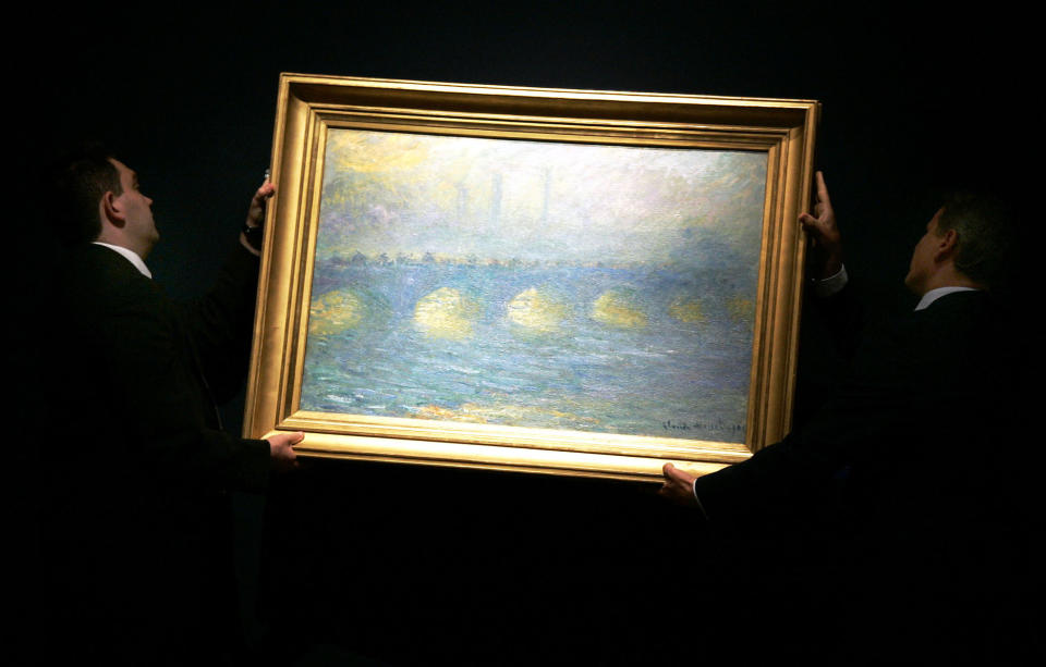 FILE - Two staff hang a Claude Monet 1904 painting 'Waterloo Bridge, temps couvert', for display at Christie's in London, Thursday, June 14, 2007. The painting was one of 60 pieces from the Paul G. Allen collection auctioned by Christie's in New York, on Wednesday, Nov. 9, 2022, bringing $1.5 billion in a single night. It sold for $64.5 million. (AP Photo/Sang Tan, File)