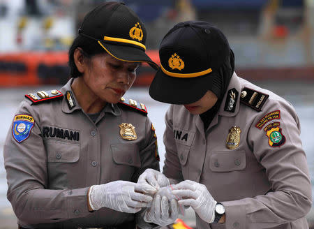 Police personnel identify recovered belongings believed to be from the crashed Lion Air flight JT610 at Tanjung Priok port in Jakarta, Indonesia, October 30, 2018. REUTERS/Edgar Su