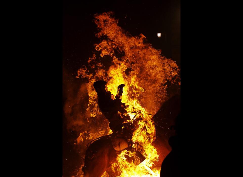 A man rides a horse through a bonfire in San Bartolome de Pinares, Spain, Monday, Jan. 16, 2012, in honor of Saint Anthony, the patron saint of animals. On the eve of Saint Anthony's Day, hundreds ride their horses trough the narrow cobblestone streets of the small village of San Bartolome during the 'Luminarias' a tradition that dates back 500 years and is meant to purify the animals with the smoke of the bonfires and protect them for the year to come. (Daniel Ochoa de Olza, AP)