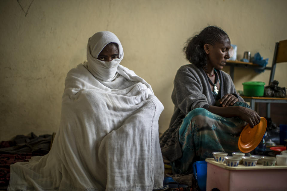 Wegahta Weldie, 21, left, an accounting student from Mai Kadra who recalled stepping on dead bodies as her family hid in a maize garden and then walked hundreds of kilometers to reach Mekele, sits as another woman makes coffee at the Hadnet General Secondary School, which has become a makeshift home to thousands displaced by the conflict, in Mekele, in the Tigray region of northern Ethiopia Wednesday, May 5, 2021. The Tigray conflict has displaced more than 1 million people, the International Organization for Migration reported in April, and the numbers continue to rise. (AP Photo/Ben Curtis)