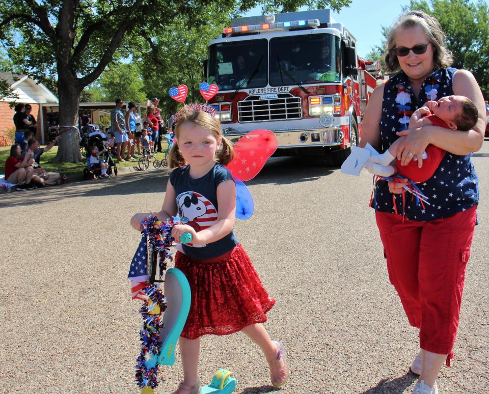Anne Reno carries great-grandson Atlas Reno, 8 weeks, while granddaughter Harper Reno, 5, scooters along ahead of a fire truck during Monday's Hillcrest Fourth of July parade.