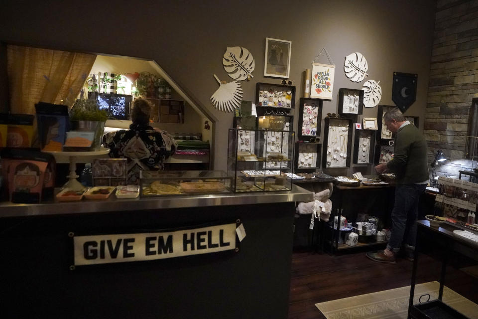 Jewelry and greeting card buyer Julie Archibald, left, and owner Nathan Waldon work while Waldon is interviewed at a Nathan & Co. store in Oakland, Calif., Monday, Dec. 12, 2022. Small retailers say this year looks much different than the last "normal" pre-pandemic holiday shopping season of 2019. They're facing decades-high inflation forcing them to raise prices and making shoppers rein in the freewheeling spending seen in 2021 when they were flush with pandemic aid and eager to spend. (AP Photo/Jeff Chiu)