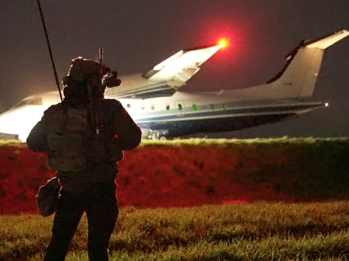 A Latvian special forces officer watches as a C146-A Wolfhound aircraft takes off from a rural highway, about two hours from Riga. (Jean-Francois Bisson/CBC News - image credit)