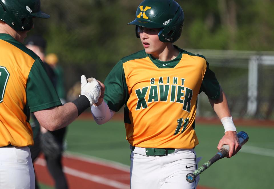 St. X’s Landon Akers (11) got a fist bump from teammate Jake Gregor (20) after scoring a run against Trinity at the St. X High School in Louisville, Ky. on April 27, 2022.  St. X won 8-2.