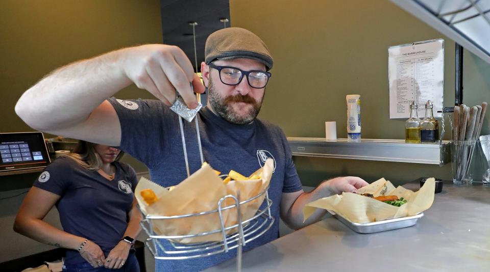 Barrelhouse owner Nick Jones helps to serve food as it's put in the window Wednesday, Sept. 6, 2023, in Akron, Ohio.