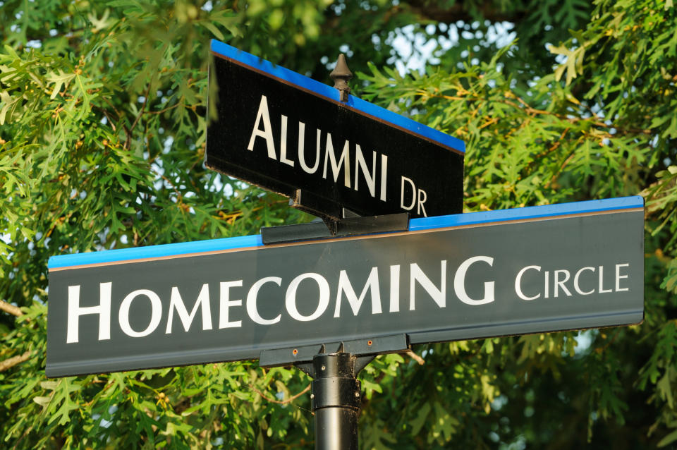 a street sign that crosses at "Alumni Dr" and "Homecoming Circle"