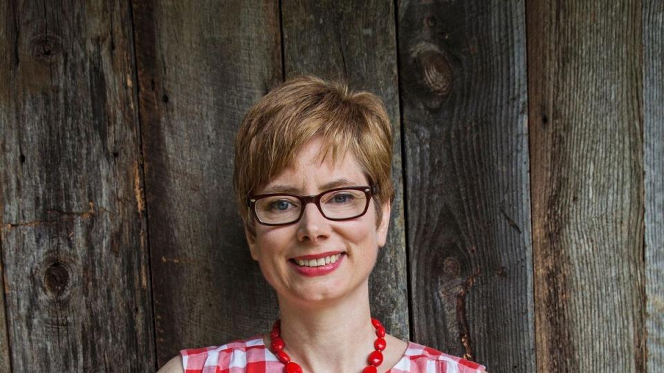 a woman in a red gingham dress holding a blueberry crumb pie