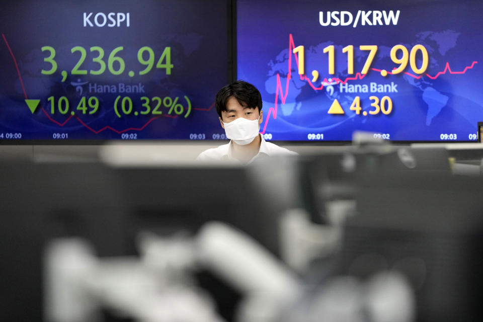 A currency trader walks by the screens showing the Korea Composite Stock Price Index (KOSPI), left, and the foreign exchange rate between U.S. dollar and South Korean won at the foreign exchange dealing room in Seoul, South Korea, Friday, June 4, 2021. Asian shares mostly slipped Friday, dragged lower by a decline in technology stocks on Wall Street.(AP Photo/Lee Jin-man)