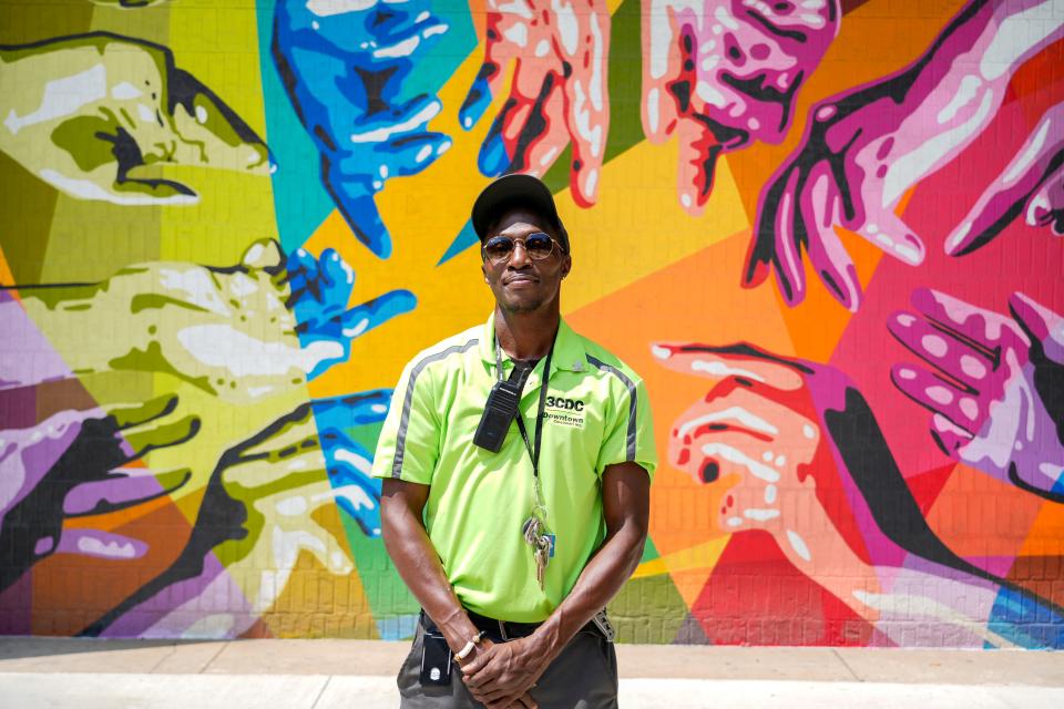 Lashun Woodard poses in front of a mural in the Court Street Historic District. As a 3CDC ambassador, he monitors one of the busiest spots in Downtown Cincinnati near Kroger-on-the-Rhine.