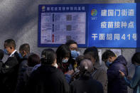 A group of women wearing face masks to help curb the spread of the coronavirus use their smartphone to make appointment as residents line up to receive booster shots against COVID-19 at a vaccination site near a residential area in Beijing, Friday, Oct. 22, 2021. China's capital Beijing has begun offering booster shots against COVID-19, four months before the city and surrounding regions are to host the Winter Olympics. (AP Photo/Andy Wong)