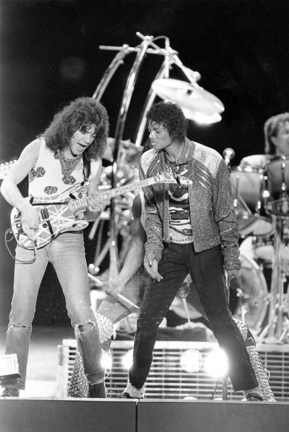 FILE - This July 14, 1984 file photo shows Van Halen guitarist Eddie Van Halen, left, performing "Beat It" with Michael Jackson during Jackson's Victory Tour concert in Irving, Texas. Van Halen, who had battled cancer, died Tuesday, Oct. 6, 2020. He was 65. (AP Photo/Carlos Osorio, File)