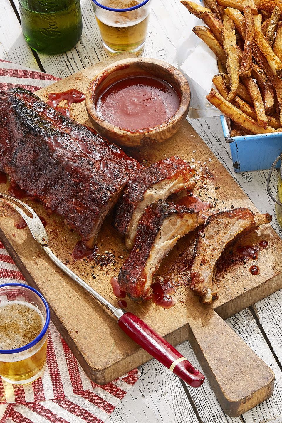 sweet heat cheerwine baby back ribs on a wooden serving board with a small bowl of the cheerwine sauce