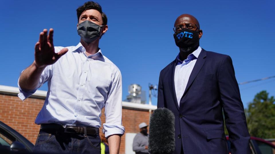 Democratic U.S. Senate candidates Jon Ossoff and Rev. Raphael Warnock hand out lawn signs at a campaign event on October 3, 2020 in Lithonia, Georgia. (Photo by Elijah Nouvelage/Getty Images)