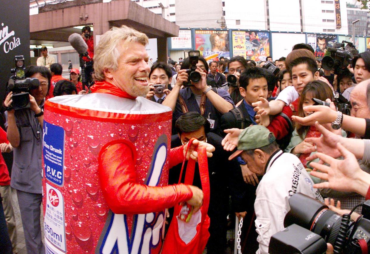 British tycoon Richard Branson hands out free colas in downtown Tokyo 23 April 1999 during a sales promotion for the Virgin Cola to break into the Japanese softdrink market. Japan's cola market is dominated by Coca Cola with 85 percent and Pepsico Inc. with 13 percent but Branson reckons even a few percentage points of lucrative market will pay off.  (ELECTRONIC IMAGE)   AFP PHOTO/Yoshikazu TSUNO (Photo by YOSHIKAZU TSUNO / AFP) (Photo by YOSHIKAZU TSUNO/AFP via Getty Images)