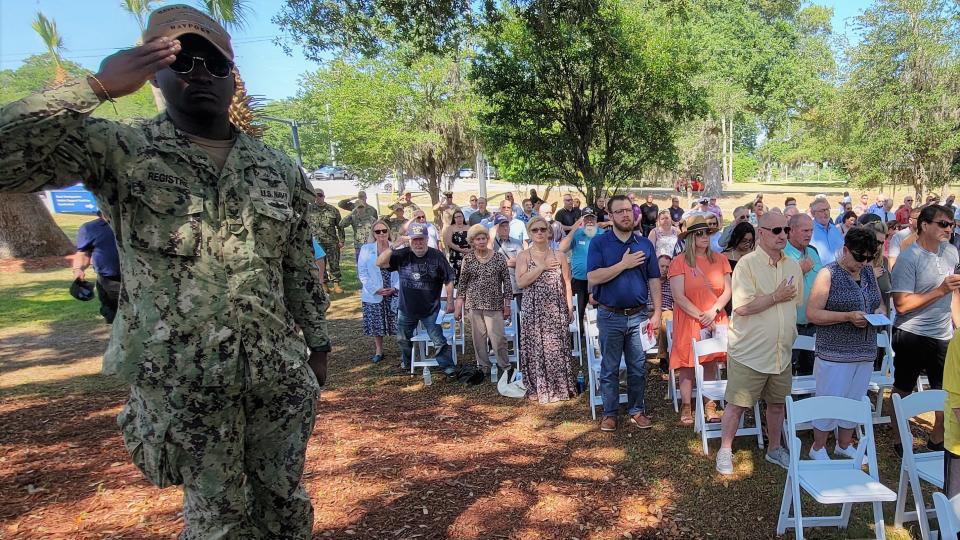 Active duty and retired U.S. Navy sailors salute as others listen while taps is played to end Tuesday's memorial to those who died in the 1987 attack on the USS Stark.