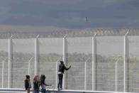 Migrants walk past the barbed wire fence on the main access route to the Ferry harbour Terminal in Calais, northern France, July 30, 2015. REUTERS/Pascal Rossignol