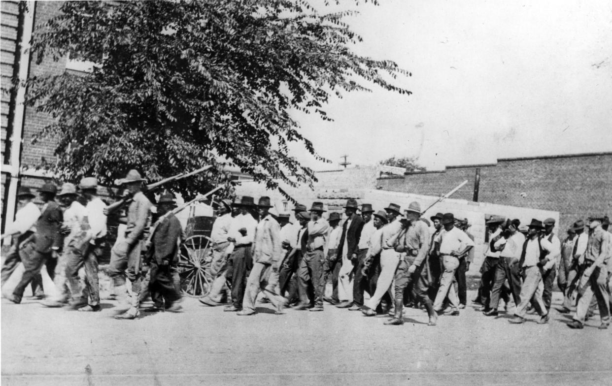 A group of National Guard Troops, carrying rifles with bayonets attached, escort unarmed African American men to the detention center at Convention Hall, after the Tulsa Race Massacre, Tulsa, Oklahoma, June 1921. (Oklahoma Historical Society/Getty Images)