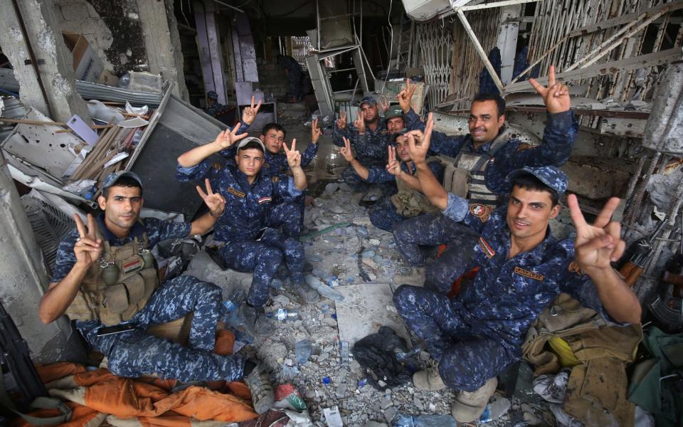 Members of the Iraqi federal police flash the sign for victory in celebration in the Old City of Mosul on July 8, 2017 - Credit: AFP