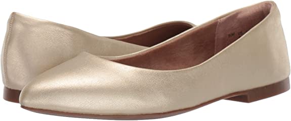 Side view of a pair of gold pointed toe flats.