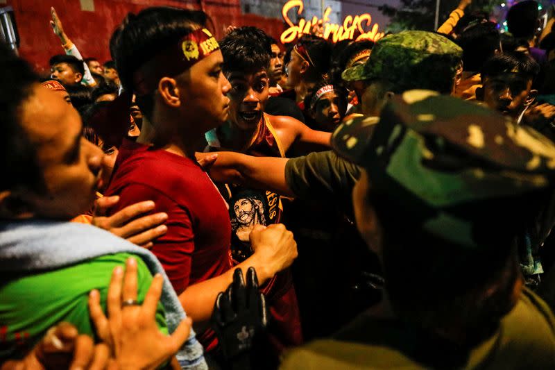 Filipino devotees argue with cops surrounding the carriage of the Black Nazarene during the annual procession to celebrate its feast day in Manila