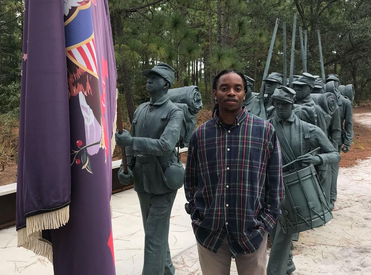 Cameron Art Museum's cultural curator, Daniel Jones, with Stephen Hayes' "Boundless" sculpture on the museum grounds. Some of the faces in the sculpture are of descendants of soldiers who fought for the Union in the Civil War with the U.S. Colored Troops.