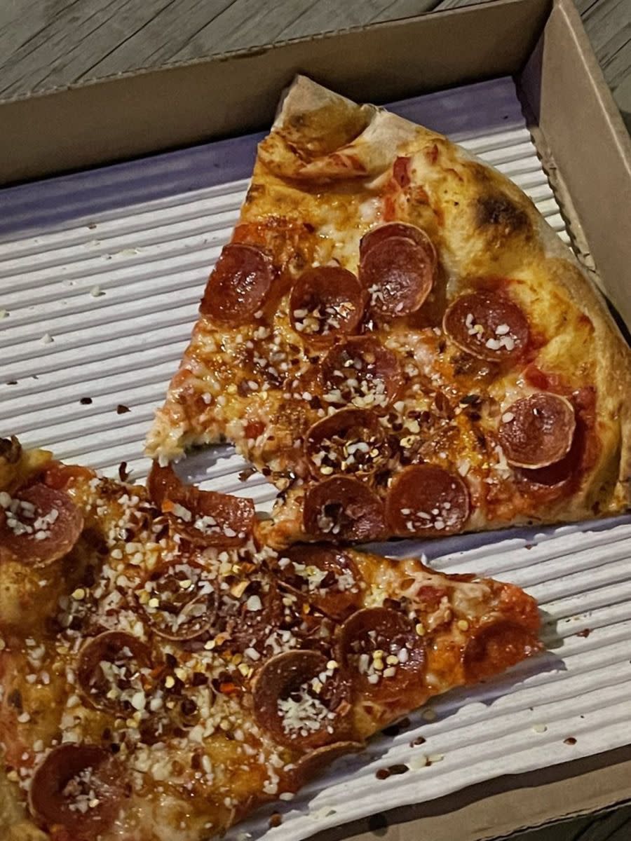 Two slices of pepperoni pizza in box, Old Town Pizza, Portland, Oregon, on a rustic wooden table