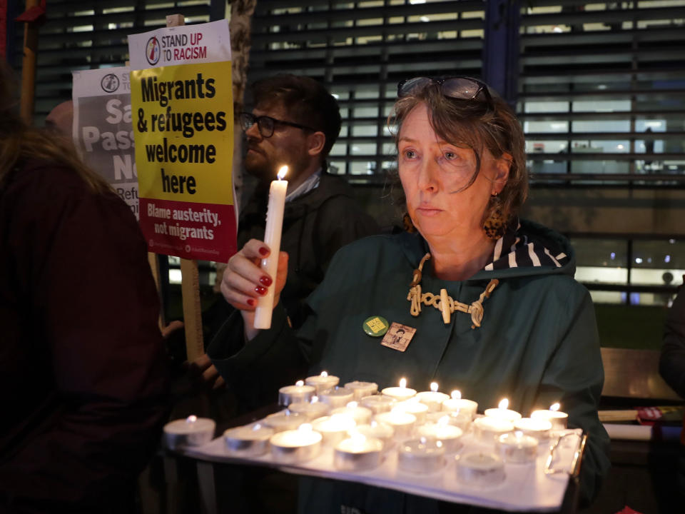 Demonstrators hold banners and candles during a vigil for the 39 lorry victims, outside the Home Office in London, Thursday, Oct. 24, 2019. Authorities found 39 people dead in a truck in an industrial park in England on Wednesday and arrested the driver on suspicion of murder in one of Britain's worst human-smuggling tragedies. (AP Photo/Kirsty Wigglesworth)