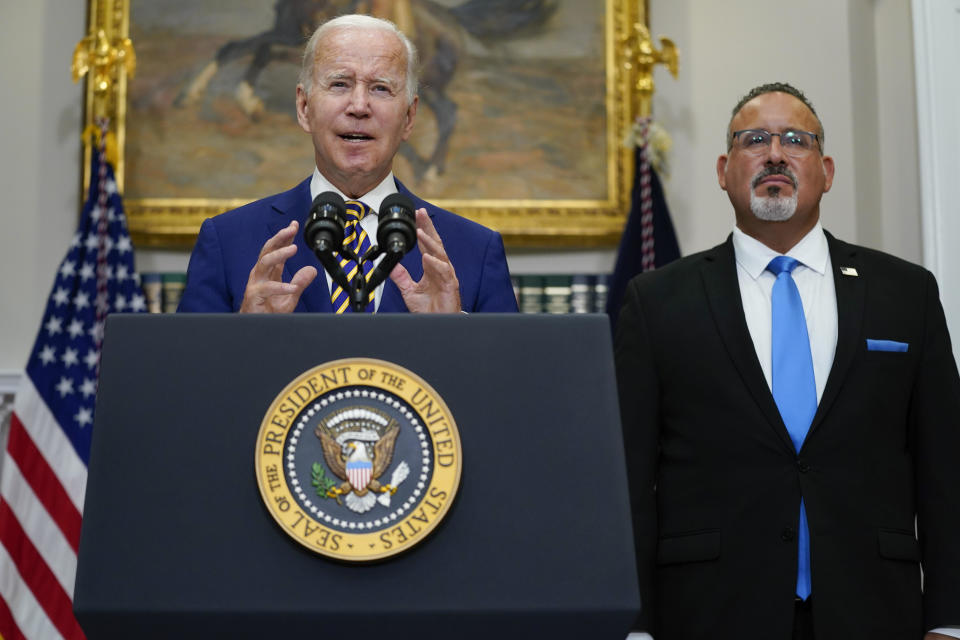 President Joe Biden speaks about student loan debt forgiveness in the Roosevelt Room of the White House, Aug. 24, 2022, in Washington. Education Secretary Miguel Cardona listens at right.  / Credit: Evan Vucci / AP