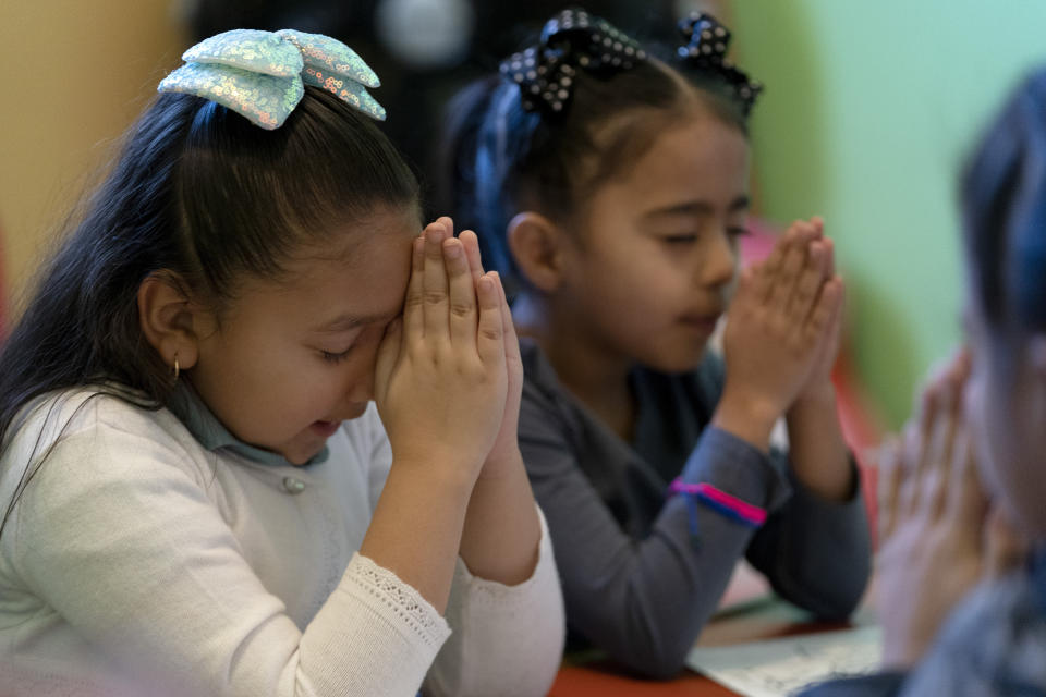 Gaby Meza Rodriguez, de 7 años, a la izquierda, reza con otros niños durante una sesión de la escuela dominical mientras sus padres asisten a un servicio religioso, el domingo 17 de diciembre de 2023 en Fort Morgan, Colorado. Los padres de Meza Rodriguez, que tienen cuatro hijos nacidos en Estados Unidos, incluida ella, están en un limbo legal mientras solicitan un permiso de residencia. (AP Foto/Julio Cortez)