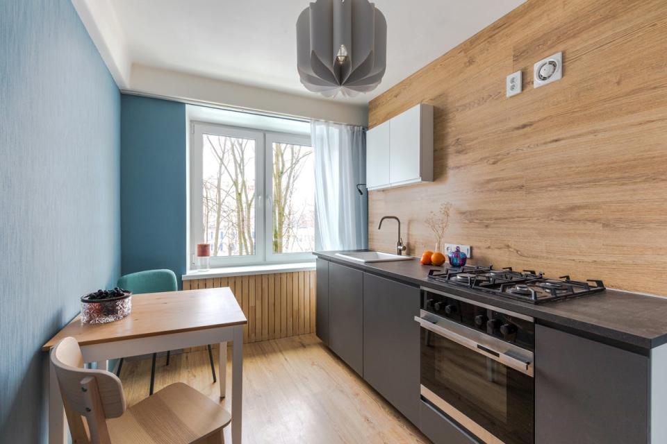 Minimalist two-tone kitchen with a wooden backsplash that doubles as an accent wall