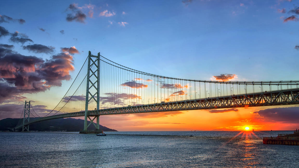 Long suspension bridge over water at sunset